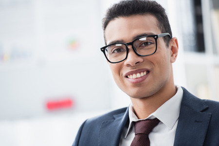 portrait of handsome young businessman in eyeglasses smiling at cameraの写真素材