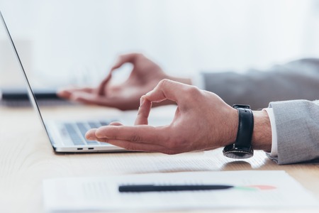 close-up partial view of businessman meditating while working with laptop in office