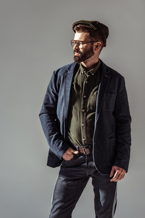 handsome bearded man with hand in pocket isolated on greyの写真素材