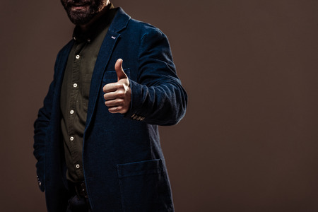 cropped view of man showing thumb up isolated on brownの写真素材