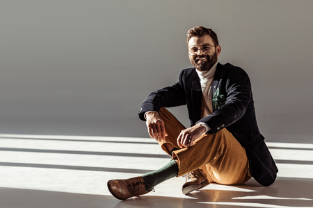 smiling bearded man sitting on floor and looking at cameraの写真素材