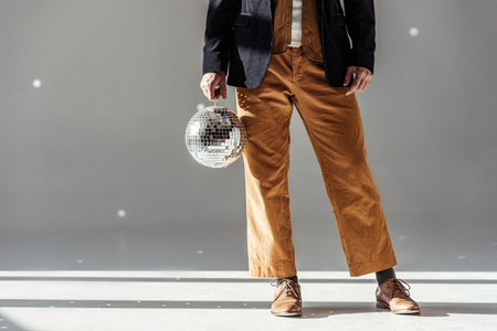 cropped view of man holding mirror ball on grey background