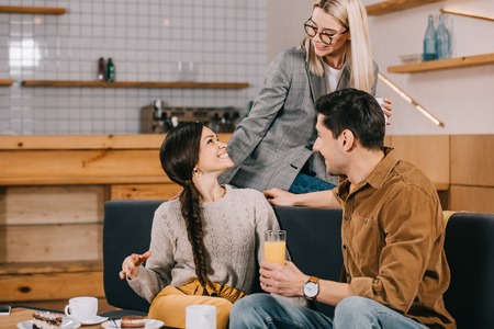 smiling woman looking at friend while sitting in cafe