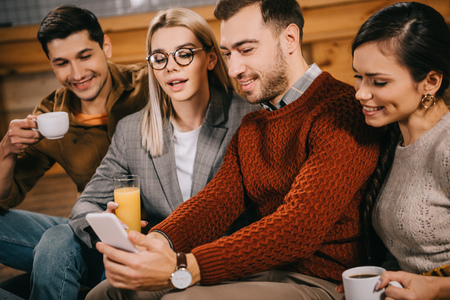 cheerful group of friends taking selfie and holding drinksの写真素材