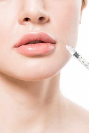 cropped shot of young woman making beauty injection in lips isolated on whiteの写真素材