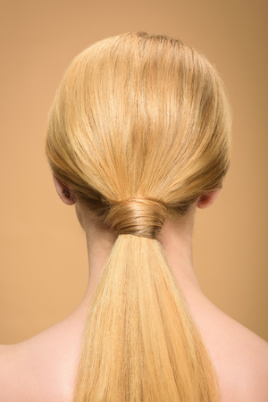rear view of young blonde woman with long straight smooth hair isolated on beigeの写真素材