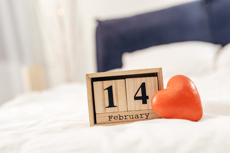 selective focus of wooden calendar with 14 february lettering and red heart toy on Valentines dayの写真素材