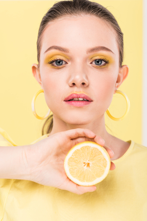 beautiful stylish girl holding lemon, looking at camera and posing isolated on limelightの写真素材