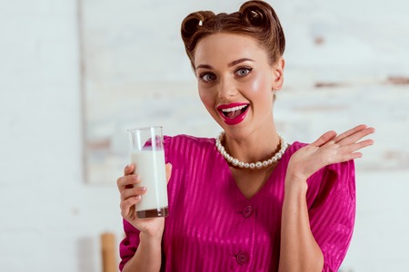 Beautiful pin up girl holding glass of milk and waving handの写真素材