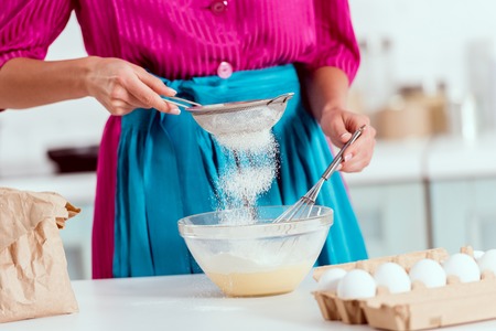 Partial view of woman sieving flour to bowlの写真素材