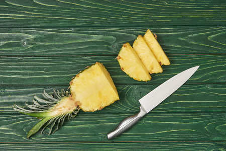 top view of sliced ripe pineapple on green wooden tableの写真素材