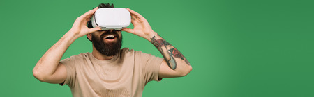 smiling bearded man using Virtual reality headset isolated on green