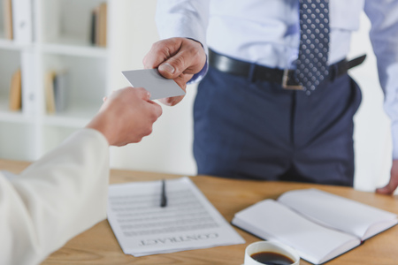 cropped view of man giving empty business card to female colleagueの写真素材
