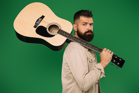 bearded male guitarist holding acoustic guitar, isolated on greenの写真素材
