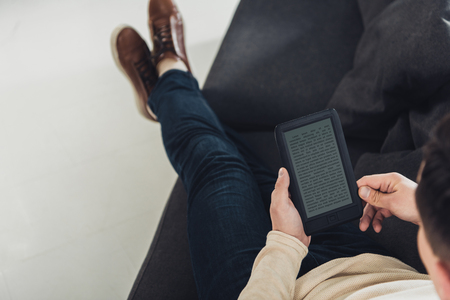 top view of man reading ebook while sitting on sofaの写真素材