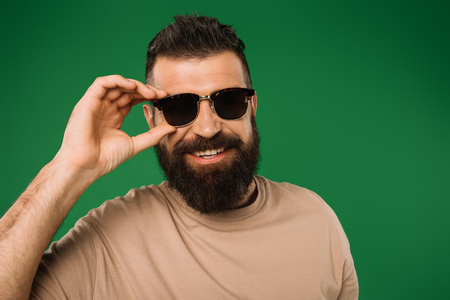 smiling bearded man in sunglasses, isolated on green