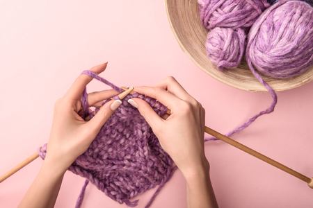 partial view of woman knitting yarn on pink backgroundの写真素材