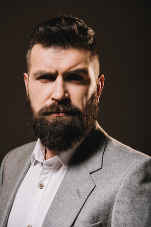 handsome brunette beard businessman in jacket isolated on brownの写真素材