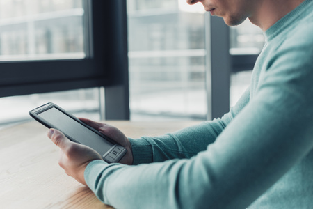 cropped view of man holding e-book with blank screenの写真素材