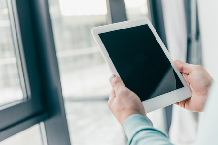 cropped view of man holding digital tablet with blank screen in hands