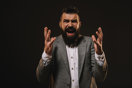 aggressive beard businessman gesturing and screaming isolated on brownの写真素材