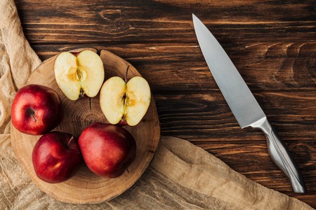 top view of red delicious apples on stump, knife and fabric on wooden tableの写真素材