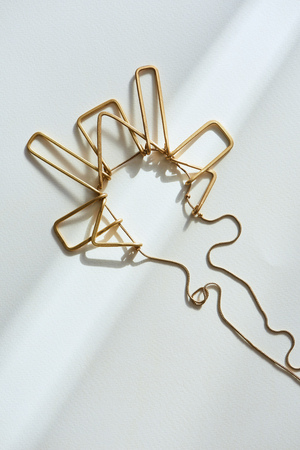 top view of beautiful golden necklace on white surface with sunlightの写真素材
