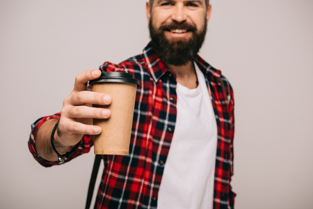 bearded smiling man in checkered shirt holding coffee to go isolated on greyの写真素材