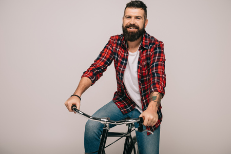 handsome smiling man riding bicycle isolated on grey