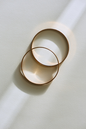 top view of two beautiful golden rings on white surface with sunlightの写真素材