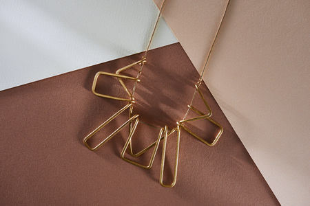 top view of beautiful luxury necklace on white and beige surface with sunlightの写真素材