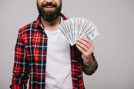 cropped view of bearded man holding dollar banknotes isolated on greyの写真素材