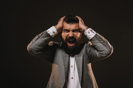 angry beard businessman screaming isolated on brownの写真素材
