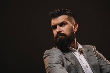 handsome thoughtful businessman looking away isolated on brownの写真素材