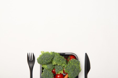 Top view of cutlery and vegetables in bowl isolated on whiteの写真素材