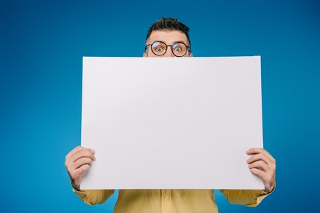 handsome man holding blank placard isolated on blue