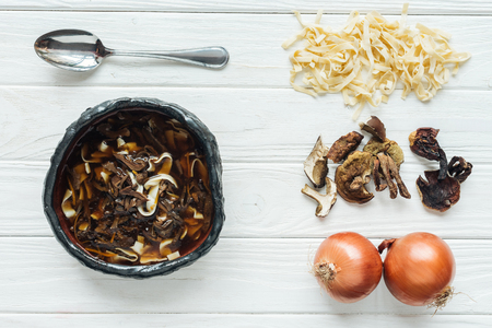 top view of traditional mushroom soup with spoon and ingredients on white wooden backgroundの写真素材
