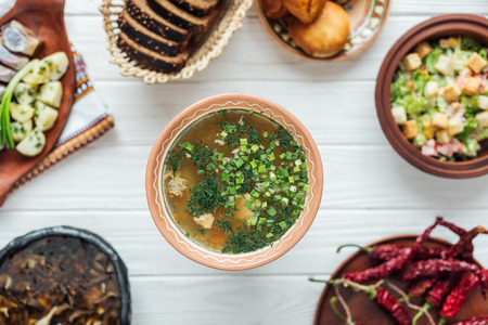 selective focus of traditional fish soup with green onion and dishes around on white wooden backgroundの写真素材
