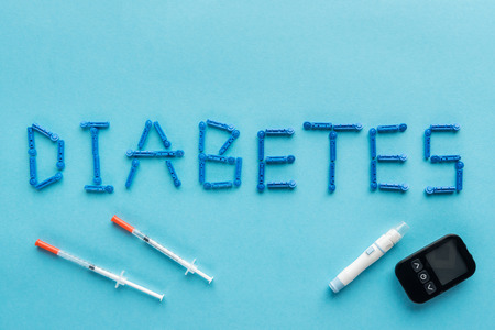 "diabetes" word with syringes and medical equipment on blue backgroundの写真素材