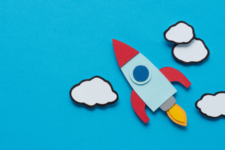 top view of cardboard rocket with clouds on blue background, setting goals conceptの写真素材