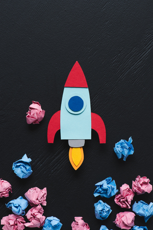 cardboard rocket with pink and blue crumpled paper balls on black background, setting goals conceptの写真素材