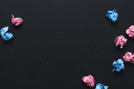 top view of scattered pink and blue crumpled paper balls on black background, think different conceptの写真素材