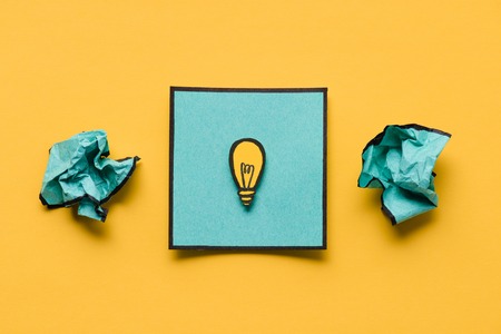 Crumpled paper and note with light bulb drawing on yellow background, ideas conceptの写真素材