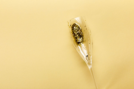 close-up view of champagne glass with golden confetti on beige backgroundの写真素材
