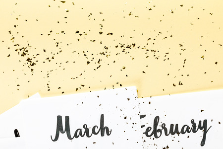 top view of march and february calendar and golden confetti on beige background