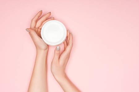 cropped of view of female hands with body cream isolated on pink with copy spaceの写真素材