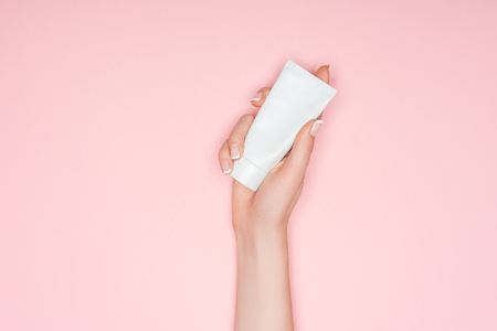 cropped view of woman holding hand cream isolated on pink with copy spaceの写真素材