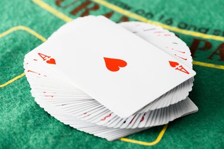 selective focus of playing card with hearts suit on deck at green poker table