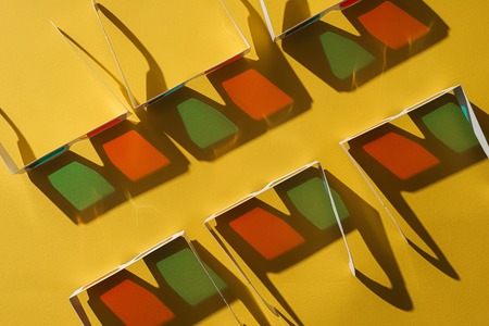 top view of cardboard 3d glasses in two rows with shadows on yellow backgroundの写真素材