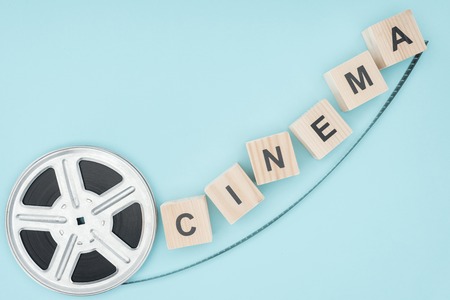 wooden cubes with "cinema" lettering and movie reel isolated on blueの写真素材